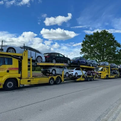 PKW-Transport auf einem gelben Autotransporter, logistische Fahrzeuglogistik, zuverlässiger Fahrzeugtransport, moderne Speditionsdienste, Fahrzeuglieferung deutschlandweit.